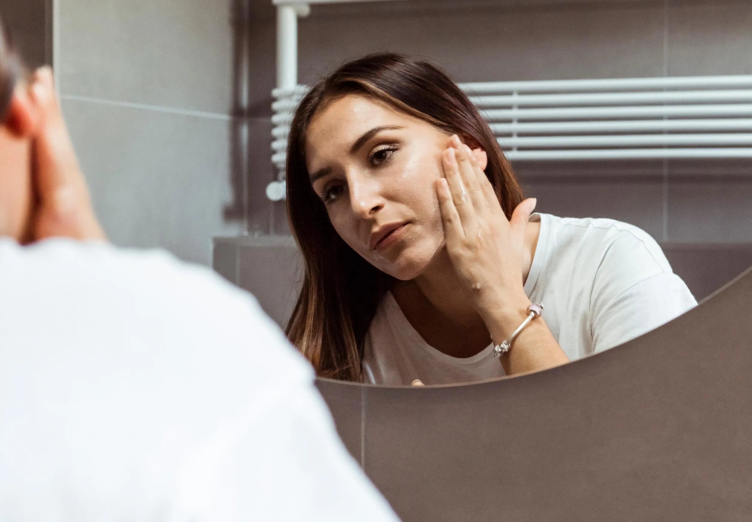 persona allo specchio che si mette la crema per la pelle